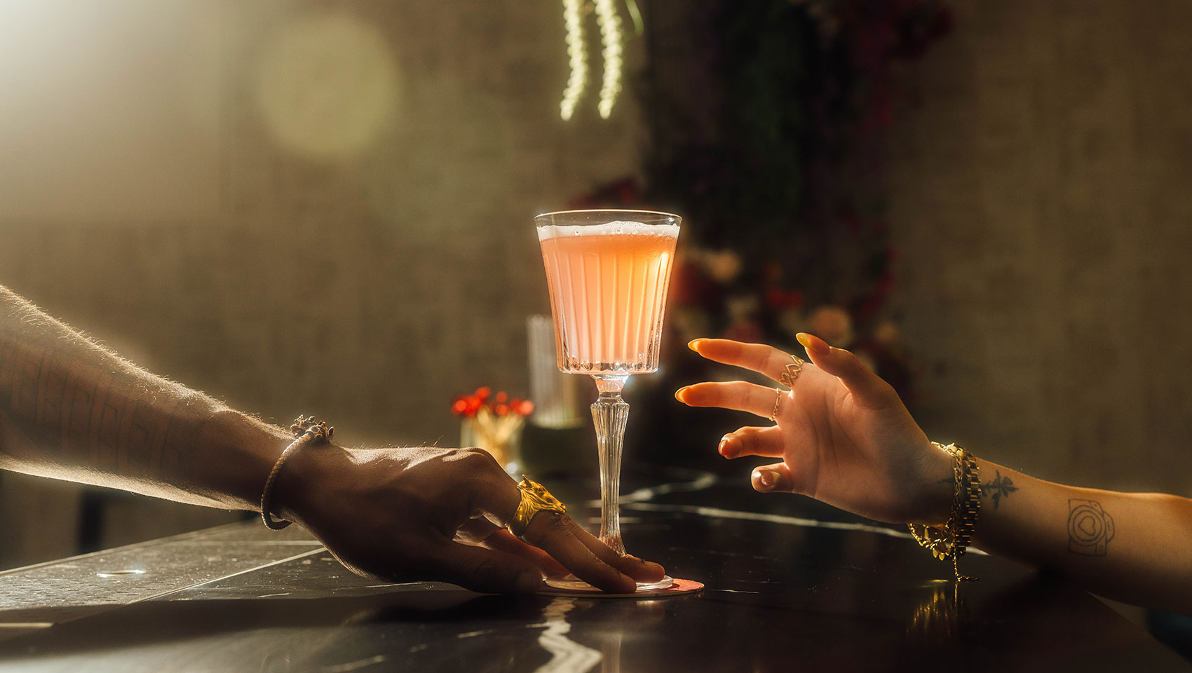 Two hands grabbing a High Praise cocktail